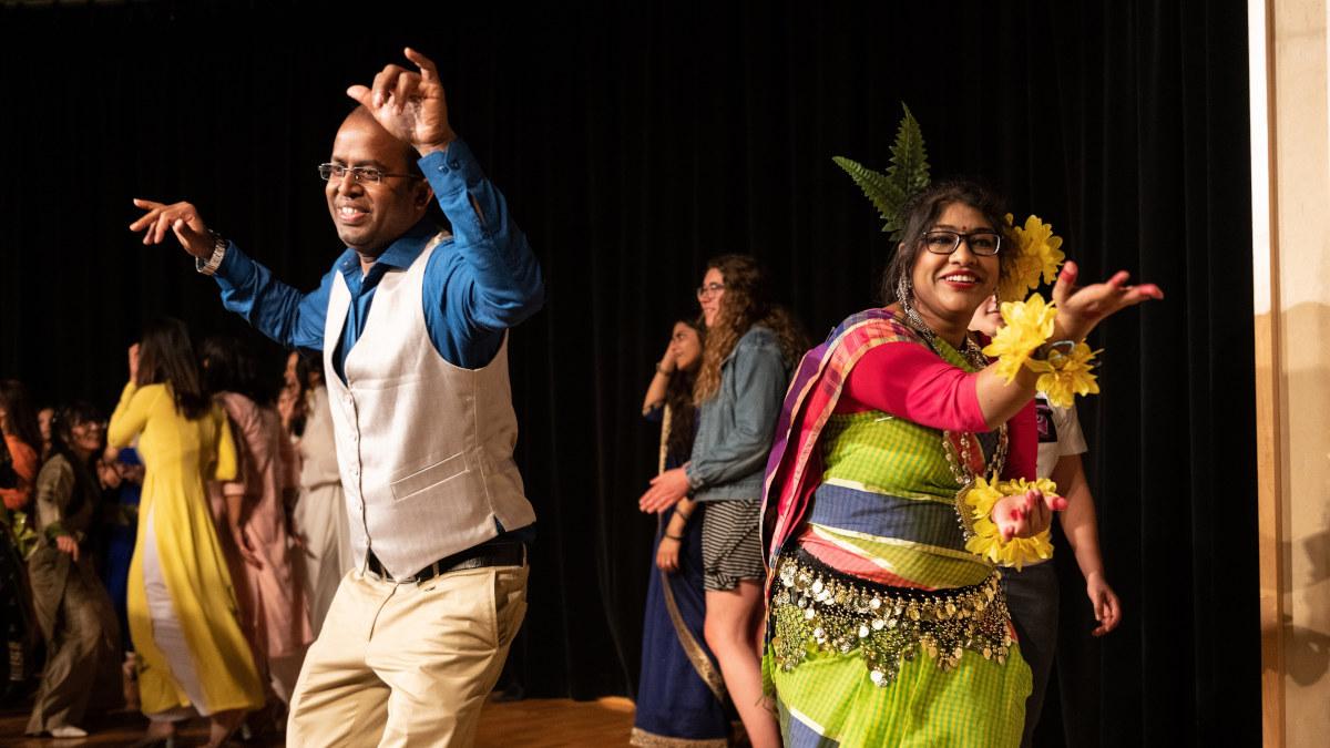 A couple dancing on stage during an open dance in traditional Bengali attire