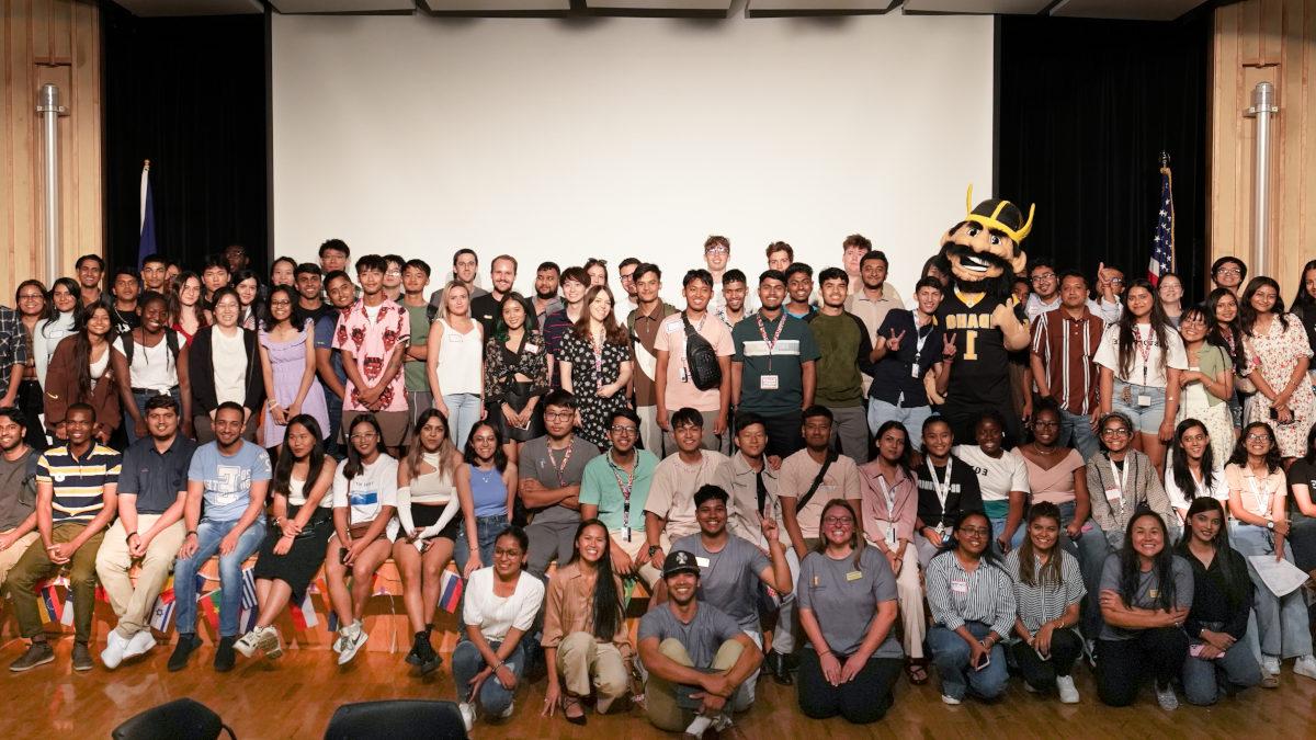 Dozens of people smile and pose for a group photo with an appearance by mascot Joe Vandal.